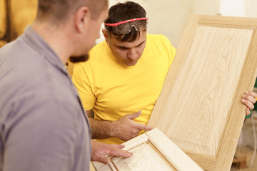 A man choosing between different timber furniture finish styles.