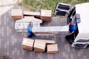 Professional movers loading timber furniture into a moving van.