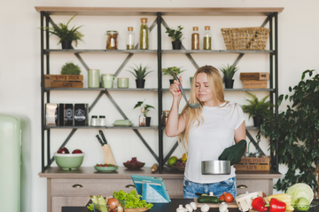 Woman cooking in kitchen with styled handcrafted wooden nesting shelves in the background.